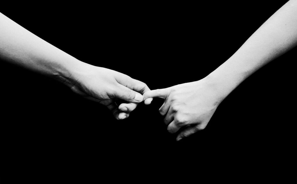 Černobílá fotografie držících se rukou.