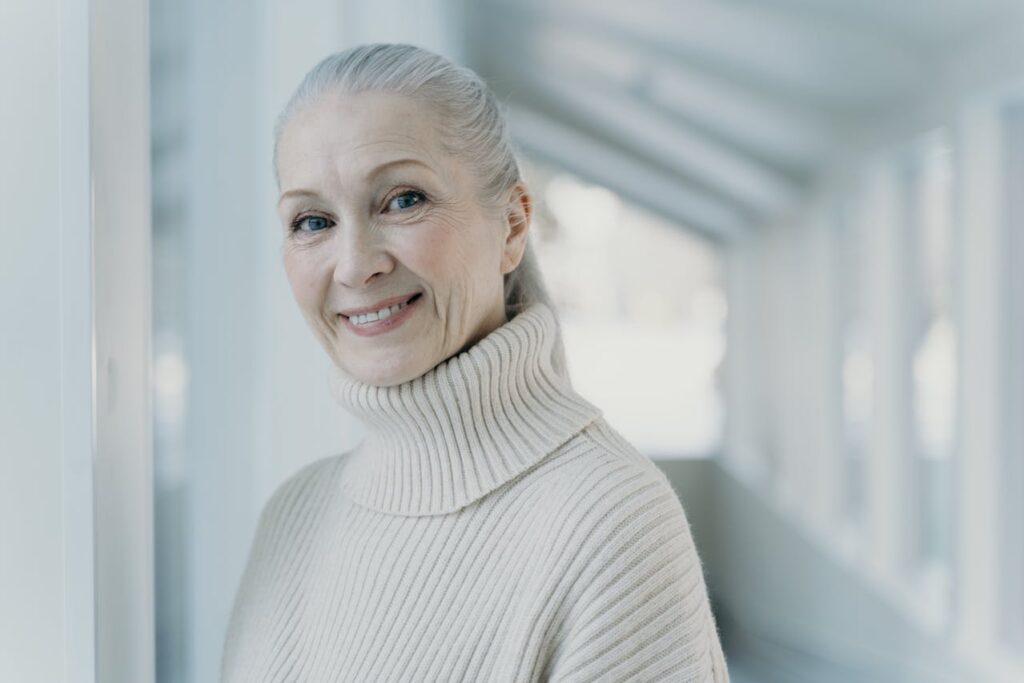 Usmívající se starší žena s bílými vlasy v copu.