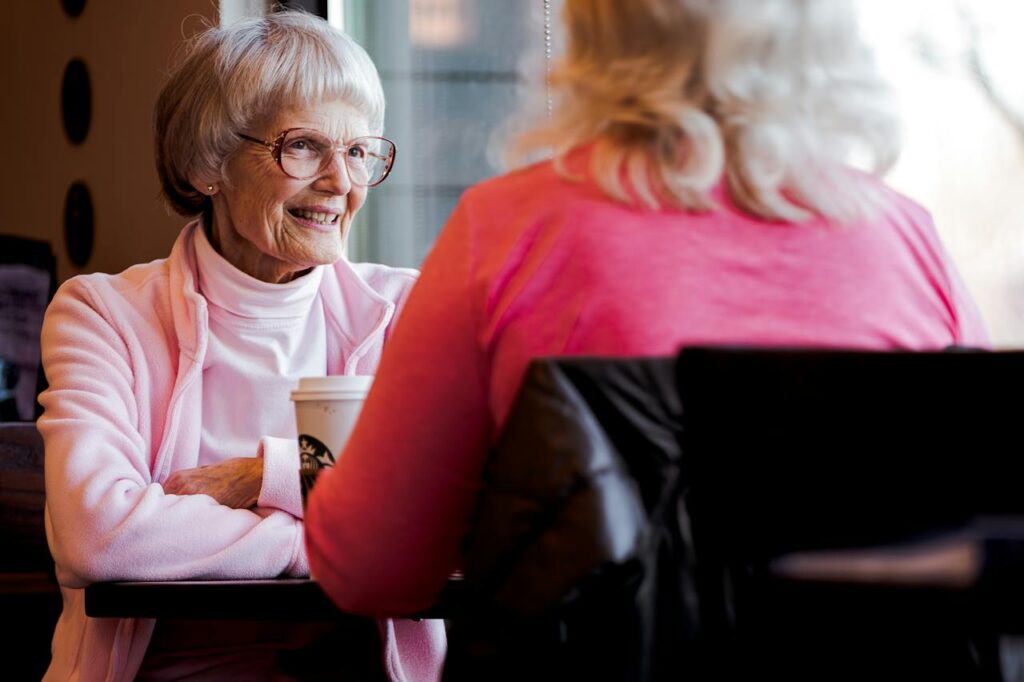 Starší žena se symetrickým střihem sedící v kavárně.
