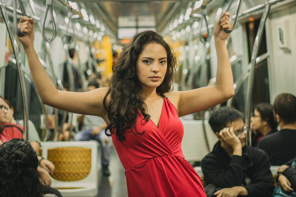 Dívka v červených šatech stojící v metru.