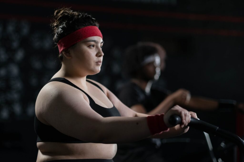 Cvičící obézní dívka ve fitness centru.
