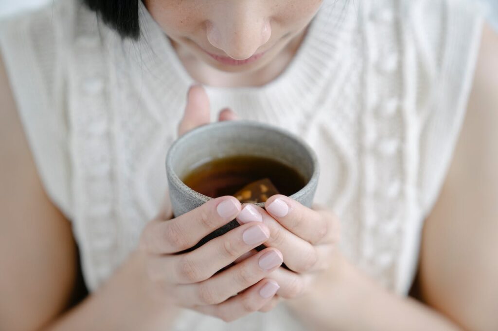 Dívka vonící k šálku s čajem.