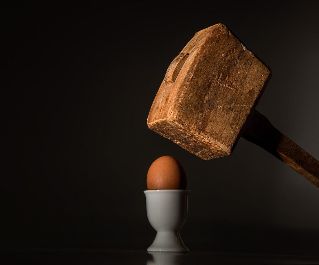 Dřevěné kladivo chystající se rozbít vejce.