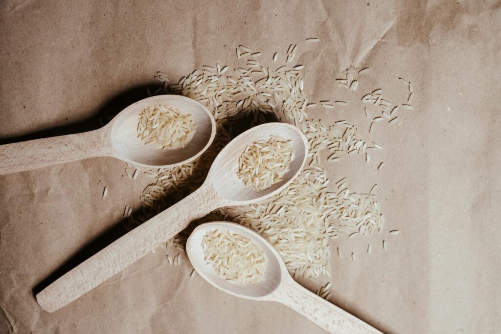 Tři lžíce s rozsypanou bílou rýží.