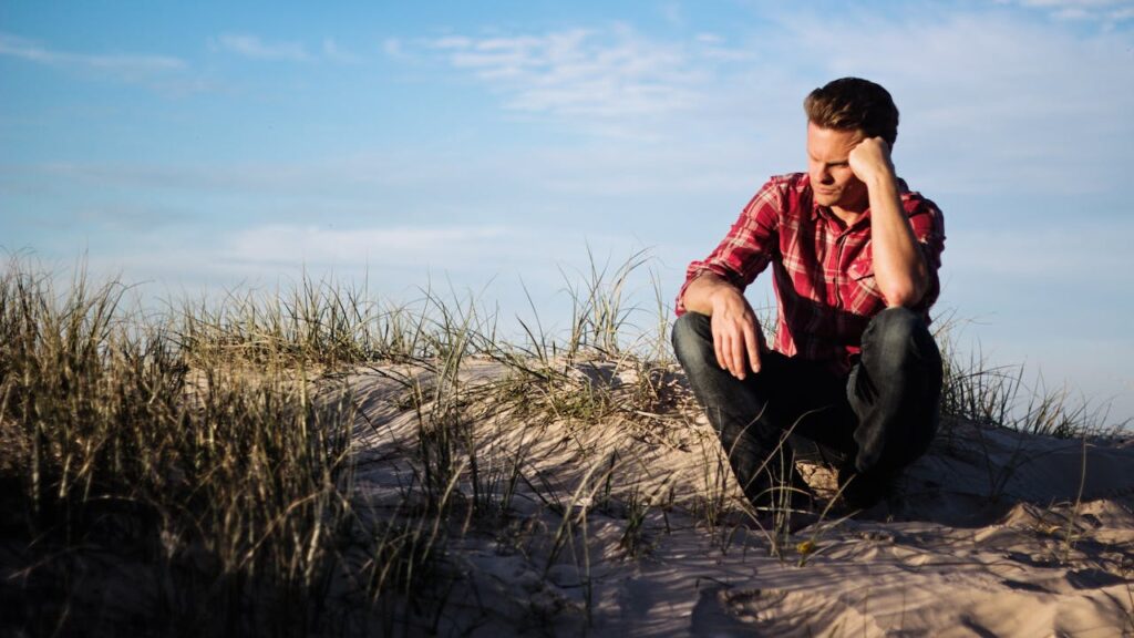 Smutně sedící muž na pláži.