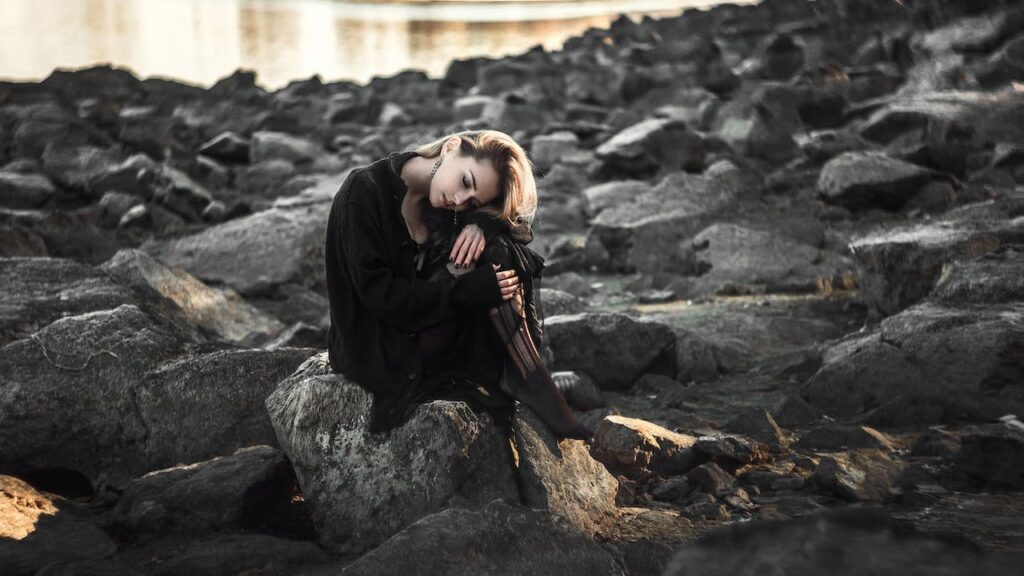 Smutná žena sedící na kamenech.