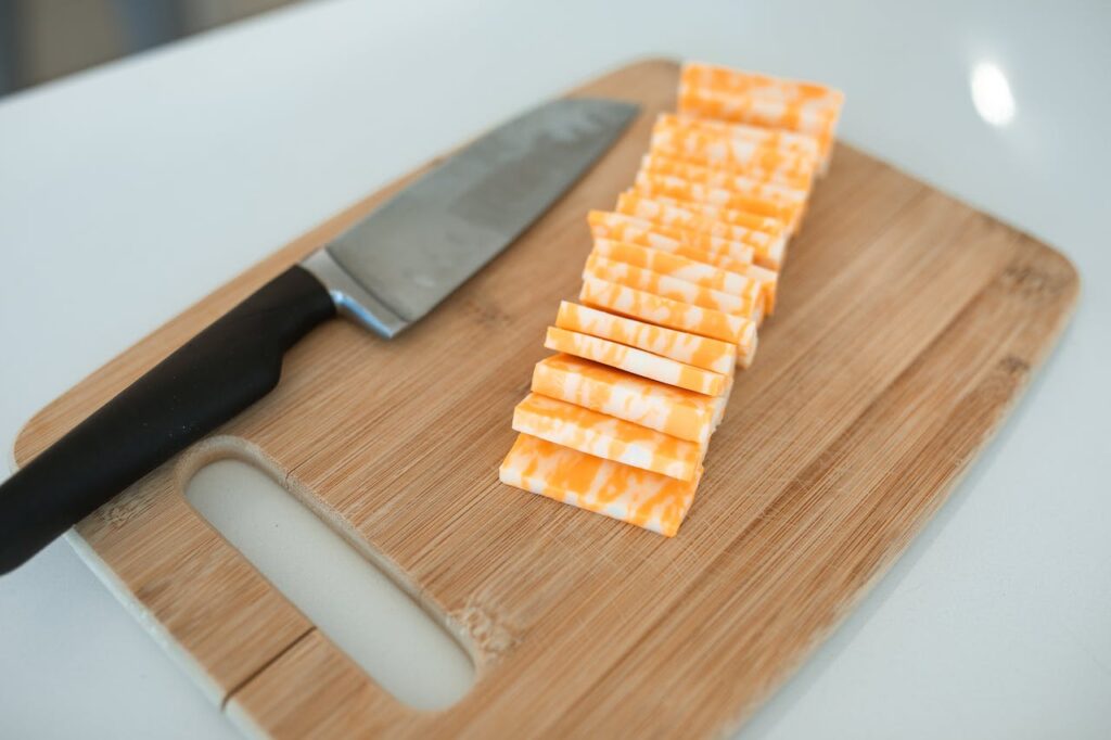 Nakrájený barevný sýr na prkénku.