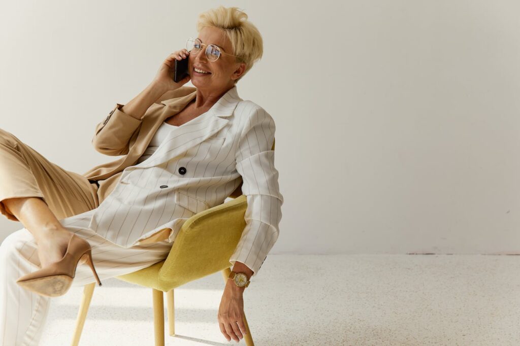 Starší telefonující usměvavá žena sedící v křesle.