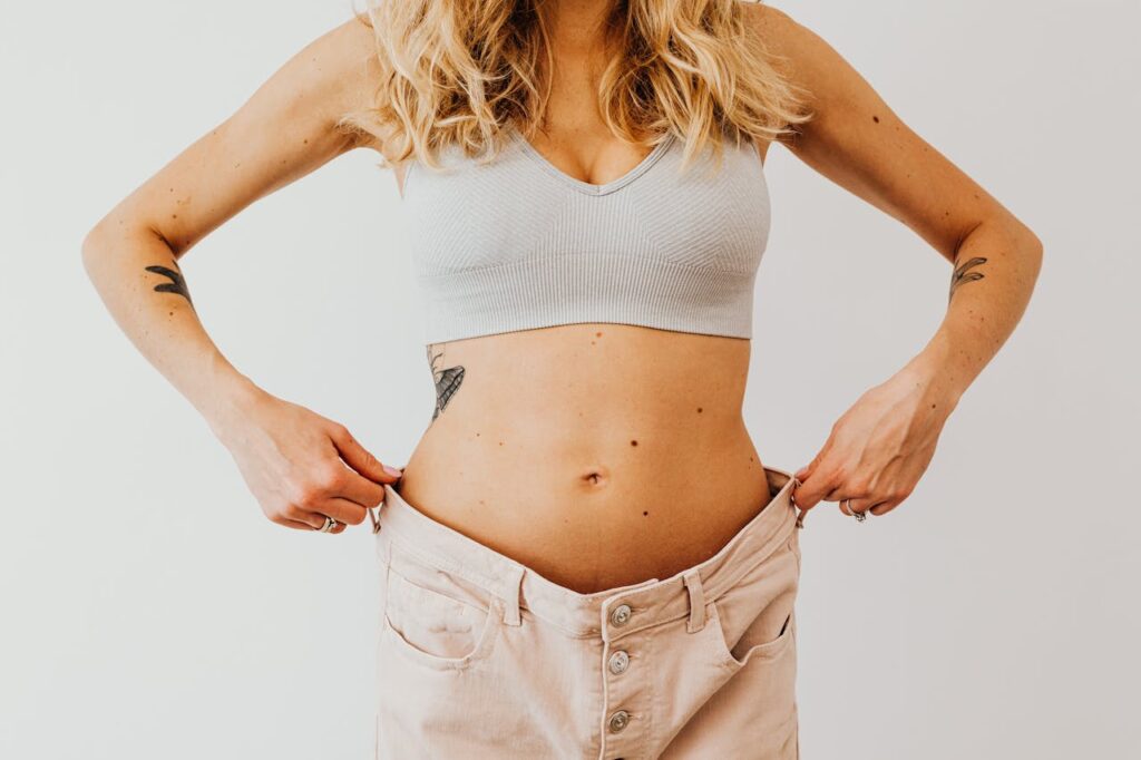 Detail na odhalené břicho ženy ve velkých kalhotách.