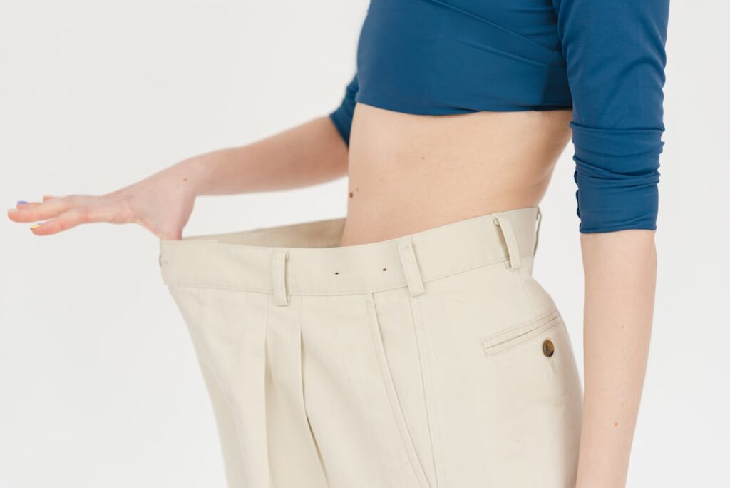 Detail na ženské břicho v kalhotách s širokým pasem.