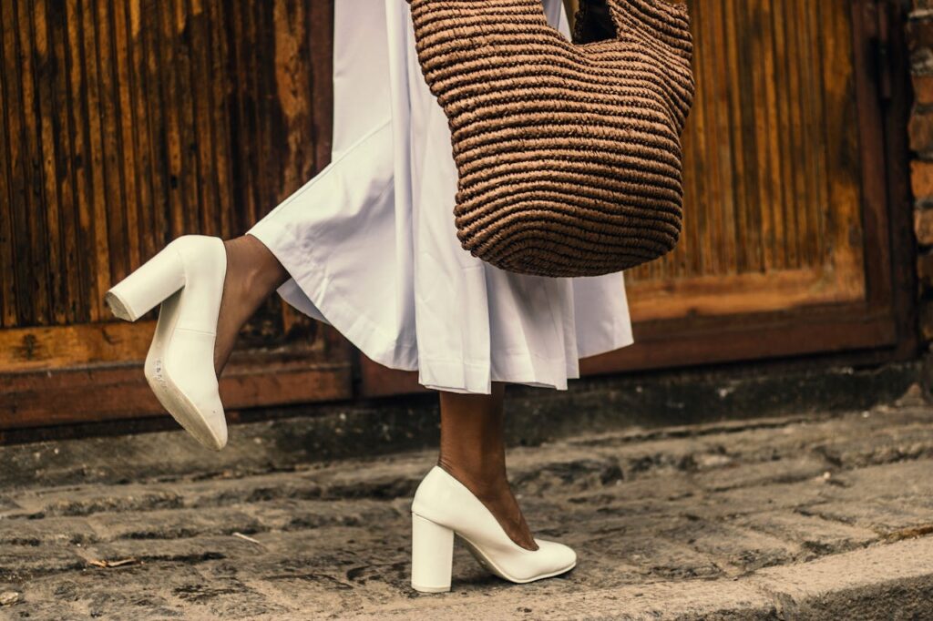 Detail na ženské nohy v bílých střevících a bílé sukni.