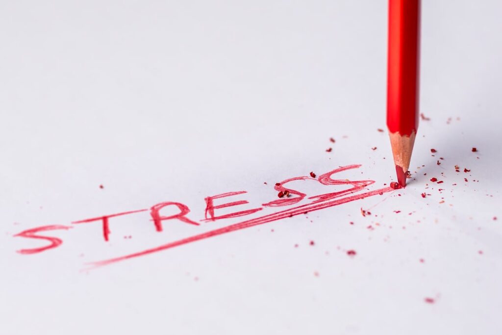 Červená pastelka píšící slovo „stress“.