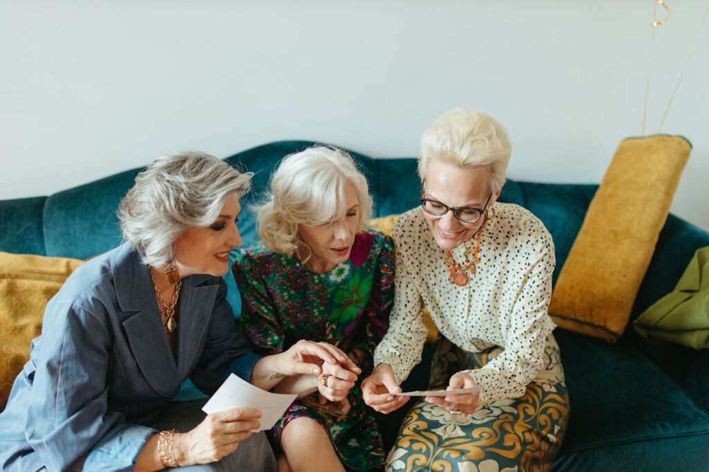 Tři starší ženy s blond vlasy prohlížející fotografie.