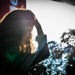 A silhouette of a woman touching her head, surrounded by nature and sunlight.