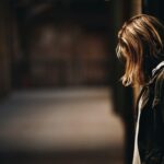 woman leaning against a wall in dim hallway