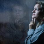 clear glass window panel casting reflection of woman touching her jaw