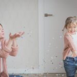 woman and child wearing beige sweater playing with confetti